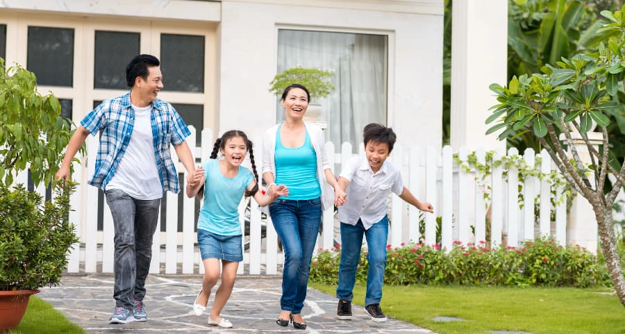 Family holding hands and walking away from a nice home with white fencing